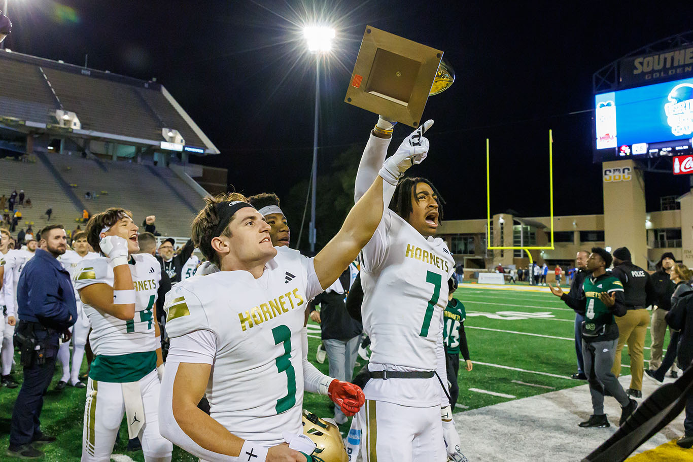 Poplarville's Nick Miller (3) and Jason Smith (7) showcase the championship trophy to its fan base.