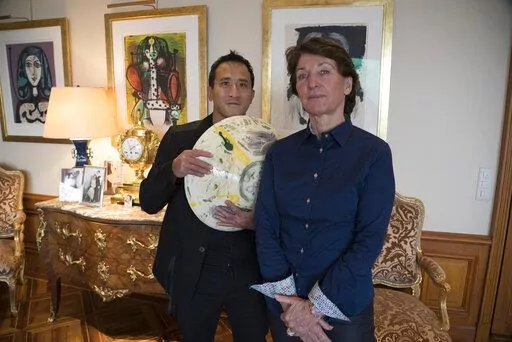 Marina Picasso, right, granddaughter of artist Pablo Picasso, and her son Florian Picasso pose with a ceramic art-work of Pablo Picasso in Cologny near in Geneva, Switzerland, Tuesday, Jan. 25, 2022. Heirs of Pablo Picasso, the famed 20th-century Spanish artist, are vaulting into 21st-century commerce by selling 1,010 digital art pieces of one of his ceramic works that has never before seen publicly — riding a fad for “crypto” assets that have taken the art and financial worlds by storm. (