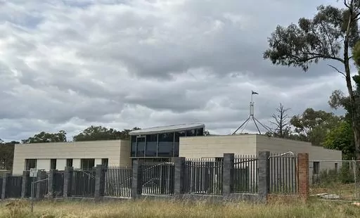 THIS CORRECTS THE PHOTOGRAPHER'S NAME TO MCGUIRK - The Australian flag flies on Parliament House, seen behind an unoccupied building on the grounds of a proposed new Russian embassy near the Australian Parliament in Canberra, Feb. 28, 2023. Australia's House of Representatives passed legislation Thursday, June 15, 2023, to prevent Russia from building a new embassy near Parliament House on security grounds. (AP Photo/Rod McGuirk)