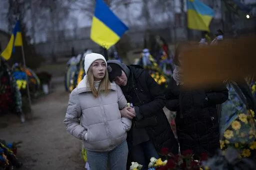 Anastasiia Okhrimenko, left, and Anna Korostenska visit the cemetery together in Bucha, Ukraine, where their partners are buried, Monday, Jan. 23, 2023. As the conflict that killed their loved ones still rages on, Anna, Anastasiia and her brother, Vadym wrestle with a question that all of war-torn Ukraine must grapple with: After loss, what comes next? (AP Photo/Daniel Cole)