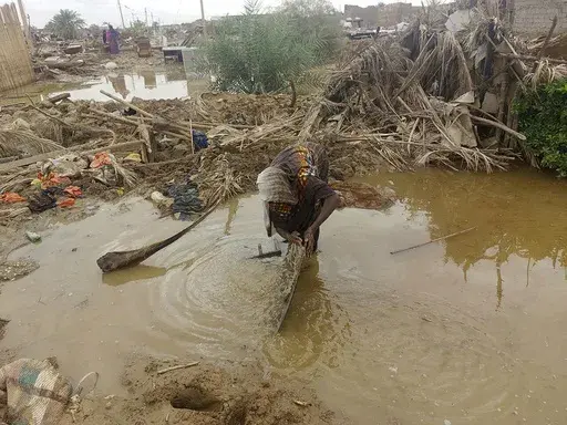 A woman sorts through floodwaters near her damaged home near the city of Abu Hamdan in Northern Sudan on Aug. 7, 2024. (AP Photo/ Samira Hassan)