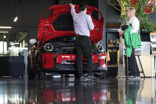 A salesperson shows an unsold 2024 Cooper SE electric hardtop to a prospective buyer at a Mini dealership Wednesday, May 1, 2024, in Highlands Ranch, Colo. On Friday, May 3, 2024, the U.S. government issues its April jobs report. (AP Photo/David Zalubowski)