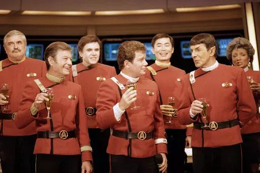 Members of the "Star Trek" crew, from left, James Doohan, DeForest Kelley, Walter Koenig, William Shatner, George Takei, Leonard Nimoy and Nichelle Nichols, toast the newest "Star Trek" film during a news conference at Paramount Studios in Los Angeles, Dec. 28, 1988. (AP Photo/Bob Galbraith, File)
