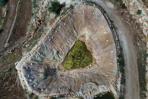 An artificial pond is seen at an agricultural field at Harf Beit Hasna village, in Dinnieh province, north Lebanon, Wednesday, Sept. 7, 2022. Farmers in a small mountainous town in Lebanon's northern Dinnieh province once could rely on rain to irrigate their crops and sustain a living. But climate change and the country's crippling economic crisis has left their soil dry and their produce left to rot. They rely on the little rain they can collect in their innovative artificial ponds to make enou