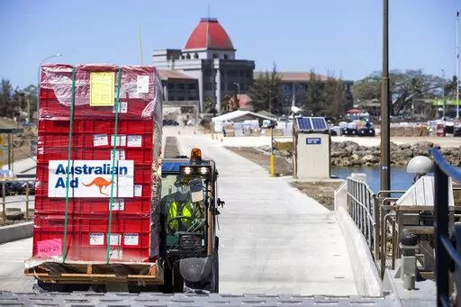In this photo provided by the Australian Defence Force, la loader is used to move aid supplies at the port at Nuku'alofa, Tonga, Thursday, Jan. 27, 2022, after HMAS Adelaide carried in the disaster relief and humanitarian aid supplies. The danger of spreading the coronavirus was underscored when nearly two dozen sailors aboard the the Adelaide were reported infected on Tuesday, raising fears they could bring the coronavirus to the small Pacific archipelago devastated by an undersea volcanic erup