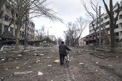 A man walks with a bicycle in a street damaged by shelling in Mariupol, Ukraine, March 10, 2022. In talks between Russia and Ukraine toward a possible cease-fire after three weeks of intense fighting, negotiators are exploring prospects of possible “neutrality” for Ukraine. (AP Photo/Evgeniy Maloletka, File)