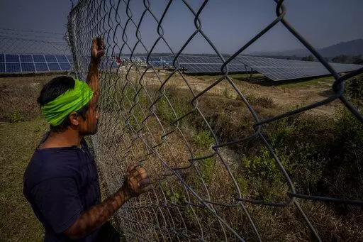 Semsong Ingti, 35, a Karbi tribal farmer whose agriculture land had been transformed to build a solar power plant stands near the plant in Mikir Bamuni village, Nagaon district, northeastern Assam state, India, Feb. 18, 2022. India will miss its renewable energy targets for the end of the year, with experts saying “multiple challenges” including a lack of financial help and taxes on imported components are stalling the clean energy industry. (AP Photo/Anupam Nath, File)