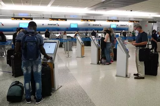 Travelers use the self-service kiosk to check in and pay for luggage at the American Airlines terminal, Thursday, April 29, 2021, in Miami.  Driven in part by pressure for contactless interactions during the pandemic, technology is rapidly evolving in the travel industry.  (AP Photo/Marta Lavandier, File)