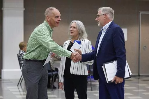 Paddy McGuire, Democrat incumbent Mason County auditor, left, shakes hands with his election opponent Republican Steve Duenkel, right, before a candidate forum, Oct. 13, 2022, in Shelton, Wash. Between is Mason County Commissioner Sharon Trask. (AP Photo/John Froschauer, File)