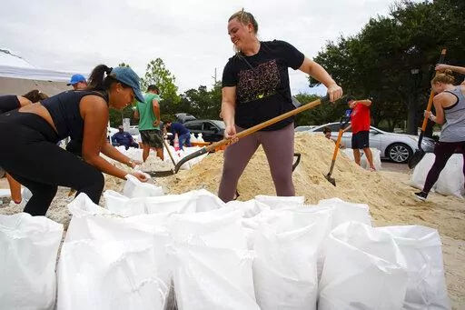 Friends Felicia Livengood, 29, and Victoria Colson, 31, fill sandbags along with hundreds of other Tampa, residents that waited for over 2 hours at Himes Avenue Complex to fill their 10 free sandbags on Sunday, Sept. 25, 2022, in Tampa, Fla. (Luis Santana/Tampa Bay Times via AP)