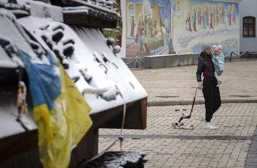 A woman walks past a display of destroyed Russian tanks and armoured vehicles after a snowfall in downtown Kyiv, Ukraine, Thursday, Nov. 17, 2022. (AP Photo/Andrew Kravchenko)