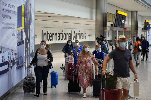 Passengers arrive at Terminal 5 of Heathrow Airport in London, Aug. 2, 2021. British Prime Minister Boris Johnson said Monday Jan. 24, 2022, his government will remove coronavirus testing requirements for vaccinated people arriving in England, news hailed by the travel industry as a big step back to normality. (AP Photo/Matt Dunham, File)