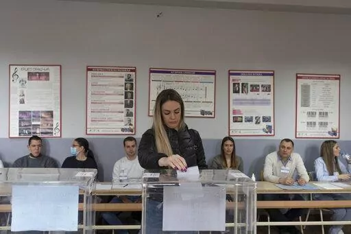 A woman votes at a polling station in Belgrade, Serbia, Sunday, April 3, 2022. Voters in Serbia cast ballots Sunday in a triple election likely to keep in power a populist government in the Balkan country that has refused to impose sanctions on Russia over the war in Ukraine.(AP Photo/Marko Drobnjakovic)