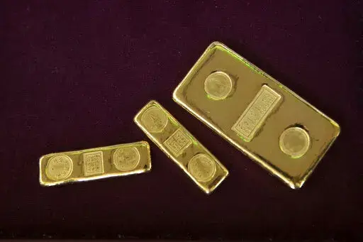 A customer puts gold bars in basket for to sell at a gold shop in Bangkok, Thailand, April 16, 2020. Russia appears to have defaulted on its foreign debt for the first time since the 1917 Bolshevik Revolution, and the U.S. and its allies are taking aim at the former Soviet Union's second-largest export industry after energy — gold. (AP Photo/Sakchai Lalit, File)