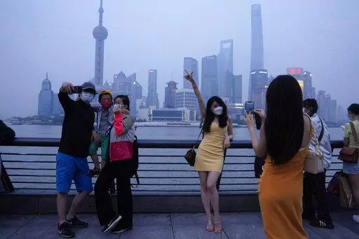 Residents pose for photos along the bund, Wednesday, June 1, 2022, in Shanghai. Traffic, pedestrians and joggers reappeared on the streets of Shanghai on Wednesday as China's largest city began returning to normalcy amid the easing of a strict two-month COVID-19 lockdown that has drawn unusual protests over its heavy-handed implementation. (AP Photo/Ng Han Guan)