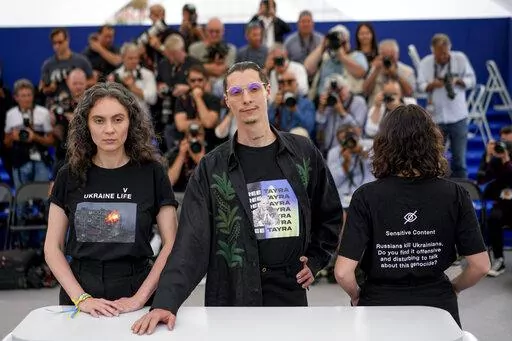 Producers Darya Bassel, left, and Yelizaveta Smith, right, wearing t-shirts that have an image of an explosion on the front and read "Sensitive Content: Russians kill Ukrainians. Do you find it offensive and disturbing to talk about this genocide?" pose with director Maksym Nakonechnyi who wears a t-shirt that reads "Free Tayra" in reference to Julia Paevska, aka Tayra, a Ukrainian medic who Russian forces have taken captive at the photo call for the film 'Butterfly Vision' at the 75th internati