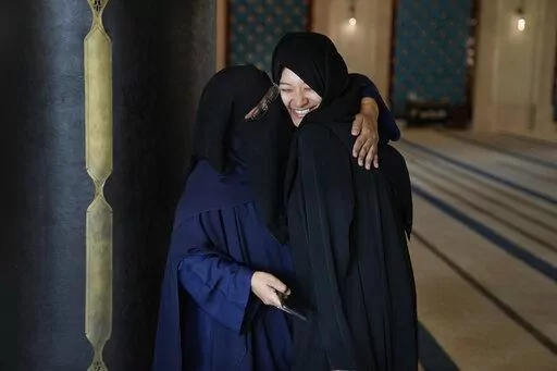 Guide Riffat Ishfaq, left from Pakistan embraces tourist Fatima Gracia from El Salvador, in Doha, Qatar, Tuesday, Dec. 6, 2022. In Qatar to enjoy the World Cup with friends, Gracia, the Salvadoran visitor took a day off from soccer to go sightseeing at the Katara mosque, where preachers have been introducing Islam in multiple languages to curious fans from around the world. (AP Photo/Jorge Saenz)