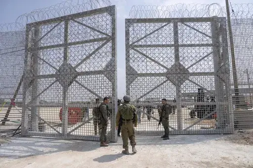 Israeli soldiers gather near a gate to walk through an inspection area for trucks carrying humanitarian aid supplies bound for the Gaza Strip, on the Israeli side of the Erez crossing into northern Gaza, on May 1, 2024. (AP Photo/Ohad Zwigenberg, File)