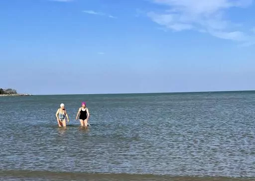 Roberta Rubin, 85, left, and Dorothy Harza, 93, wade in the water after a late-autumn swim in Lake Michigan on Nov. 10, 2022, in Evanston, Ill. Harza swims nearly daily in Lake Michigan from May to November. (Roberta Rubin via AP)