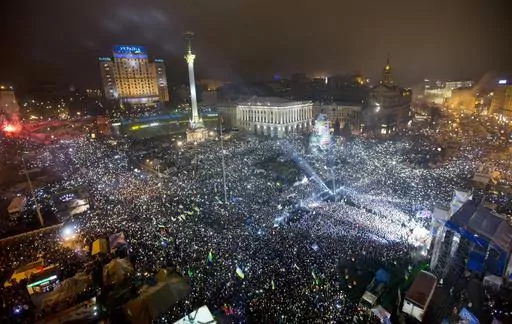 In this Jan. 1, 2014, file photo Pro-European Union activists hold lights as they sing the Ukrainian national anthem, celebrating the New Year in Kyiv's main square. At least 100,000 Ukrainians gathered in a sign of support for integration with Europe. On Nov. 21, 2023, Ukraine marks the 10th anniversary of the uprising that eventually led to the ouster of the country’s Moscow-friendly president. (AP Photo/Efrem Lukatsky, file)