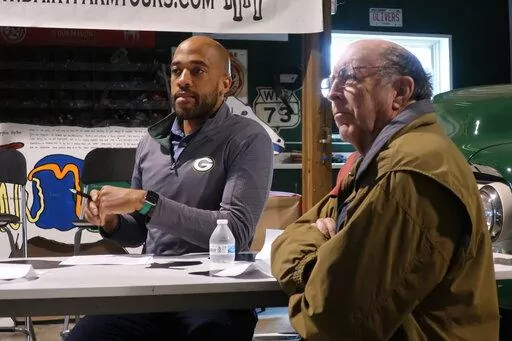 Democratic U.S. Senate candidate Mandela Barnes, left, and Maribel, Wisconsin, farmer Michael Slattery listen to a discussion about issues facing rural Wisconsin during a stop on the candidate's "Barnes for Barns" tour on Wednesday, April 13, 2022, at a dairy farm in Cambridge, Wis. Barnes is trying to appeal to rural voters as part of his campaign to win the Democratic primary and knock off Republican U.S. Sen. Ron Johnson. (AP Photo/Scott Bauer)
