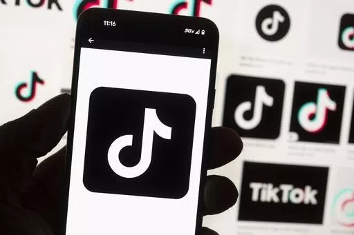The TikTok logo is displayed on a mobile phone in front of a computer screen, Oct. 14, 2022, in Boston. TikTok is gearing up for a legal fight against a U.S. law that would force the social media platform to break ties with its China-based parent company or face a ban. A battle in the courts will almost certainly be backed by Chinese authorities as the bitter U.S.-China rivalry threatens the future of a wildly popular way for young Americans to connect online. (AP Photo/Michael Dwyer, File)