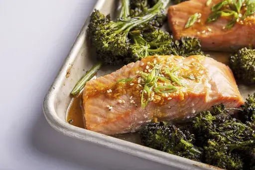 This image released by Milk Street shows a recipe for honey-miso salmon and broccolini traybake. (Milk Street via AP)