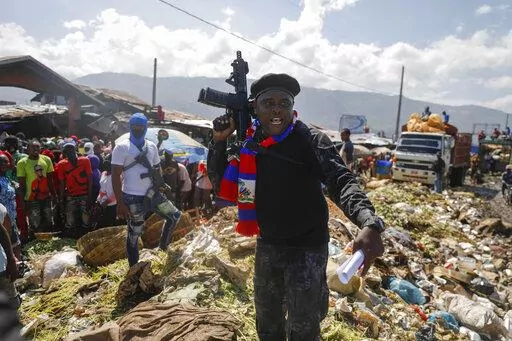 Barbecue, the leader of the "G9 and Family" gang, stands next to garbage to call attention to the conditions people live in as he leads a march against kidnapping through La Saline neighborhood in Port-au-Prince, Haiti, Friday, Oct. 22, 2021. Haiti Prime Minister Ariel Henry and 18 top-ranking officials have requested on the second week of Oct. 2022, the immediate deployment of foreign armed troops as gangs and protesters paralyze the country. (AP Photo/Odelyn Joseph, File)