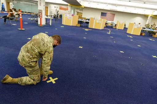 Rhode Island Army National Guard Staff Sgt. Andrew Bates pulls up tape marking a line at a coronavirus mass-vaccination site at the former Citizens Bank headquarters in Cranston, R.I., June 10, 2021. Up to 40,000 Army National Guard soldiers across the country - or about 13% of the force — have not yet gotten the mandated COVID-19 vaccine, and as the deadline for shots looms, at least 14,000 of them have flatly refused and could be forced out of the service. (AP Photo/David Goldman, File)