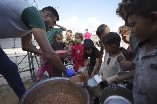 Displaced Palestinian children queue for food in a camp in Deir al-Balah, Gaza Strip, Friday, Oct. 18, 2024. (AP Photo/Abdel Kareem Hana, File)