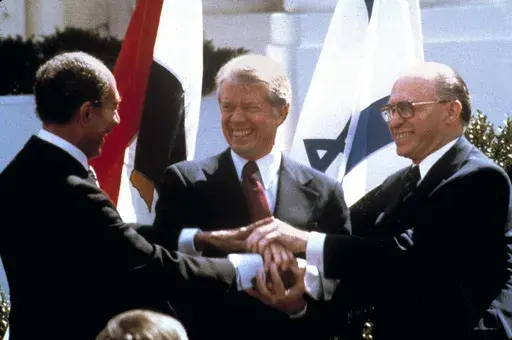 Egyptian President Anwar Sadat, left, U.S. President Jimmy Carter, center, and Israeli Prime Minister Menachem Begin clasp hands on the North lawn of the White House as they completed signing of the peace treaty between Egypt and Israel in Washington on March, 26, 1979. Egypt has threatened to void its decades-long peace treaty with Israel if Israel begins a large-scale offensive on Rafah, where some 1.4 million Palestinians shelter in densely-packed tent camps on the border with Egypt. (AP Phot