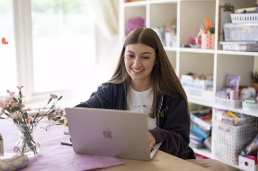 Amea Wadsworth works on her computer at her home, Friday, April 19, 2024, in San Diego. Wadsworth, who moved back home after graduating college, wanted to use her first full-time job as a chance to save, and a moment to take a hard look at her spending activity. (AP Photo/Gregory Bull)