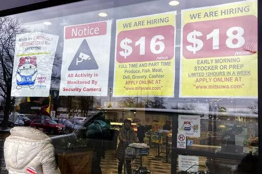 Hiring signs are displayed at a grocery store in Arlington Heights, Ill., Friday, Jan. 13, 2023. On Tuesday, the Labor Department reports on wages and benefits for U.S. workers during the October-December quarter. (AP Photo/Nam Y. Huh, File)