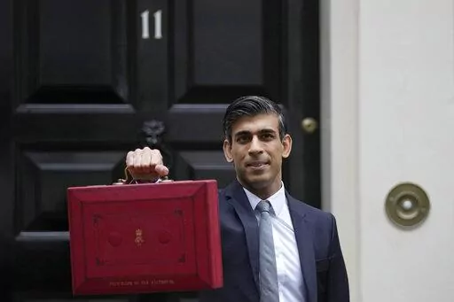 Britain's Chancellor of the Exchequer Rishi Sunak holds up the traditional ministerial red dispatch box as he leaves for the House of Commons to deliver the Budget in London, Oct. 27, 2021. Revelations that Prime Minister Boris Johnson and his staff partied while Britain was in a coronavirus lockdown have provoked public outrage and led some members of his Conservative Party to consider ousting their leader. If they manage to push Johnson out — or if he resigns — the party would hold a leade