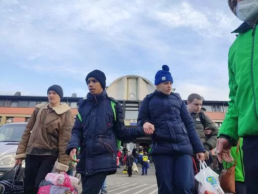 Disabled children are escorted to waiting buses, in Zahony, Hungary, Wednesday, March 2, 2022, after being evacuated from two orphanages in Kyiv, Ukraine. Some of Ukraine’s most vulnerable citizens have reached safety in Poland through an effort of solidarity and compassion that transcended borders and raised a powerful counterpoint to war. (AP Photo/Justin Spike)