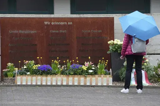 A woman looks at candles at the schoolyard of the Joseph-Koenig high school in Haltern, Germany, ten years after 16 pupils and two teachers of the school died in the Germanwings crash in the French Alps, Monday, March 24, 2025. (AP Photo/Martin Meissner)