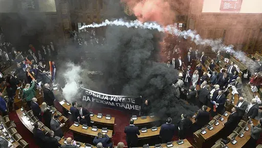 In this grab taken from video provided by RTS Serbia smoke bombs and flares are released in parliament, in Belgrade, Serbia, Tuesday, March 4, 2025. (RTS Serbia via AP)