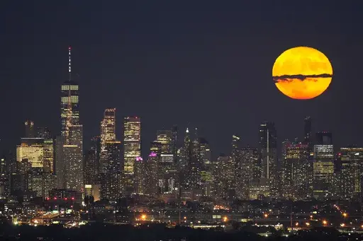 The moon rises through clouds over the skyline of lower Manhattan in this view from West Orange, N.J., Tuesday, Aug. 1, 2023, during a supermoon period. (AP Photo/Seth Wenig, File)