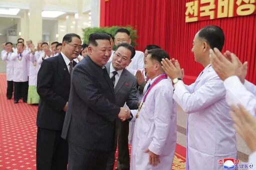 In this photo provided by the North Korean government, North Korean leader Kim Jong Un shakes hands with a health official in Pyongyang, North Korea, Wednesday, Aug. 10, 2022. Kim has declared victory over COVID-19 and ordered an easing of preventive measures. Independent journalists were not given access to cover the event depicted in this image distributed by the North Korean government. The content of this image is as provided and cannot be independently verified. Korean language watermark on