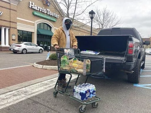 Chris Stokes picks up extra provisions at a grocery store in Norfolk, Va., on Friday Jan. 21, 2022, as the city prepares for an upcoming snowstorm.   (AP Photo/Ben Finley)