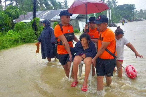 In this photo provided by the Philippine Coast Guard, rescuers evacuate residents from flood waters caused by Tropical Storm Nalgae in Hilongos, Leyte province, Philippines on Friday Oct. 28, 2022. Flash floods and landslides set off by torrential rains left dozens of people dead, including in a hard-hit southern Philippine province, where many villagers are feared missing and buried in a deluge of rainwater, mud, rocks and trees, officials said Saturday. (Philippine Coast Guard via AP)