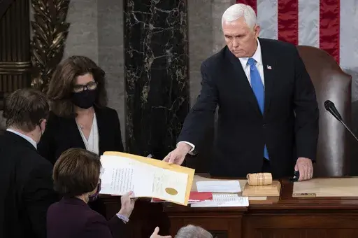 Vice President Mike Pence hands the electoral certificate from the state of Arizona to Sen. Amy Klobuchar, D-Minn., as he presides over a joint session of Congress as it convenes to count the Electoral College votes cast in November's election, at the Capitol in Washington, Jan. 6, 2021. (Saul Loeb/Pool via AP, File)