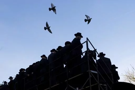 Pigeons fly above rabbis gathering for a group photo at the Chabad-Lubavitch World Headquarters, Sunday, Nov. 4, 2018, in New York. The synagogue in New York's Brooklyn borough is closely tied with Rabbi Menachem Mendel Schneerson's enduring influence in global Judaism and beyond in the three decades since his death, but it received unwanted attention in January 2024 with a brawl between some worshippers and police, part of a sequence of events that began with the discovery of a secretly dug tun