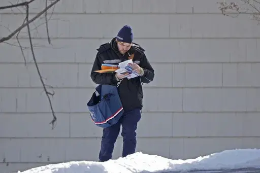 A U.S. Postal Service letter carrier delivers mail, Friday, Feb. 21, 2025, in Overland Park, Kan. (AP Photo/Charlie Riedel, File)