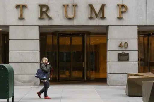 A woman walks past the Trump Building in New York's financial district, Wednesday, Jan. 13, 2021. Mazars USA LLP, the accounting firm that prepared former President Donald Trump’s annual financial statements, says the documents “should no longer be relied upon” after investigators said they found evidence he and his company regularly misstated the value of assets. (AP Photo/Mark Lennihan, File)