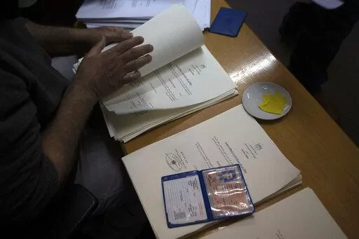 A Palestinian civil affairs employee looks for a name among the  letters officially approved by Israel, in his office in Gaza City, Monday, Jan. 3, 2022. In recent months, Israel has approved residency for thousands of Palestinians in the occupied West Bank and Gaza, allowing them to get an official Palestinian ID number that grants them the possibility to travel abroad and clear up years of uncertain legal status. (AP Photo/ Khalil Hamra)