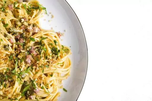 This image released by Milk Street shows a recipe for Lemon Caper Spaghetti with Pancetta and Toasted Breadcrumbs. (Milk Street via AP)
