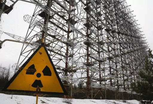 A Soviet-era top secret object Duga, an over-the-horizon radar system once used as part of the Soviet missile defense early-warning radar network, seen behind a radioactivity sign in Chernobyl, Ukraine, on Nov. 22, 2018. Among the most worrying developments on an already shocking day, as Russia invaded Ukraine on Thursday, was warfare at the Chernobyl nuclear plant, where radioactivity is still leaking from history's worst nuclear disaster 36 years ago. (AP Photo/Efrem Lukatsky, File)