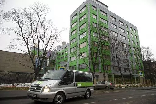 In this file photo taken on Friday, Oct. 27, 2017, a car of Russian state-owned television station RT passes by the company's office in Moscow, Russia. Britain’s communications regulator has revoked the license of Russian-backed broadcaster RT amid investigations of its coverage of the Ukraine war. The regulator, Ofcom, said it a statement that it did not consider RT’s licensee, ANO TV Novosti, to be “fit and proper to hold a U.K. broadcast license.” (AP Photo/Pavel Golovkin, FILE)
