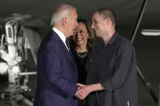 President Joe Biden, from left, and Vice President Kamala Harris greet reporter Evan Gershkovich at Andrews Air Force Base, Md., following his release as part of a 24-person prisoner swap between Russia and the United States, Aug. 1, 2024. Bloomberg News is apologizing for a premature story written about the prisoner exchange and says it has disciplined the journalists involved. The story was put out by Bloomberg hours before an embargo was lifted by the White House. (AP Photo/Manuel Balce Cenet